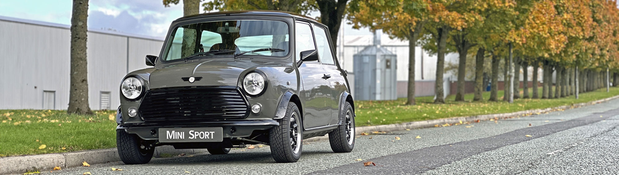 Classic Mini Spectre parked on a scenic road, showcasing its stealth-inspired Yukon Grey finish.